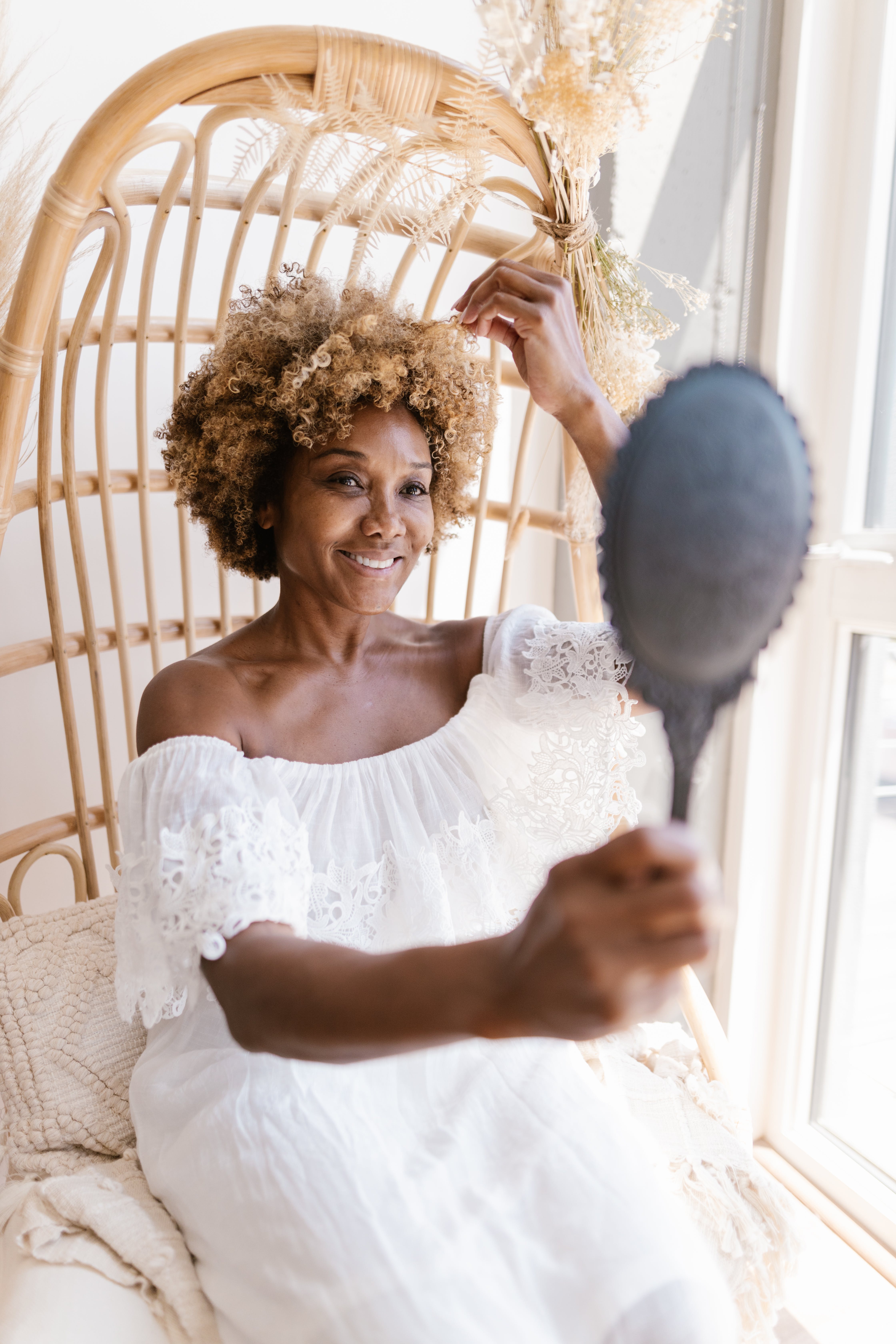 woman using a hand-held mirror to look at her curls